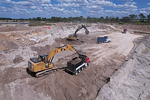 birds eye view of excavator and trucks at work picking up fill dirt