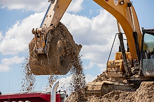 fill dirt getting dumped by an excavator into a truck