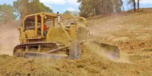 bulldozer spreads dirt and rock for a new fill layer on a commercial construction road project