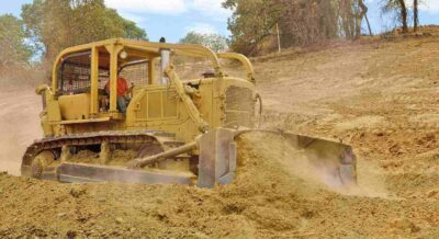 bulldozer spreads dirt and rock for a new fill layer on a commercial construction road project