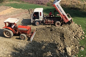 truck and a bulldozer dirt leveling on a plot of land