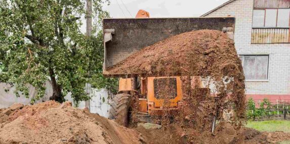 bucket of a bulldozer fills the trench with earth in an industrial zone