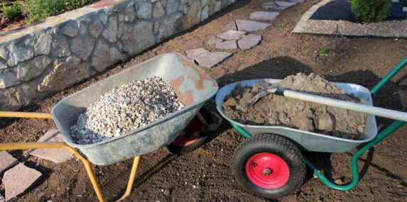 sand and a square point shovel on the cultivated soil in the summer garden under reconstruction