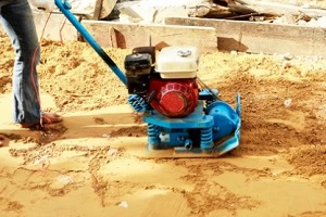 man compacting soil with compacting machine