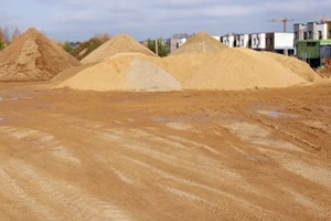 large piles of SW Florida construction sand with traces of tractor wheels on city building site