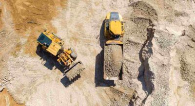 Bucket loader loading Gravel onto an Articulated hauler Truck trailer at a large construction site