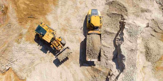 Bucket loader loading Gravel onto an Articulated hauler Truck trailer at a large construction site