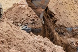 excavator backfills fill dirt pit with the front bucket