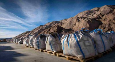 Bags of Fill Dirt Placed on Pallets in Front of Large Pile