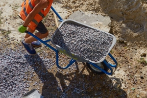 Worker Driving Wheelbarrow Filled with Gravel