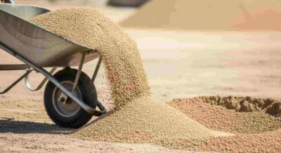 Wheelbarrow Tipping Fill Dirt on Site to Prepare Surface Before Sand Application in Lakeland, FL